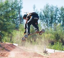 Person jumping over hill on mountainboard